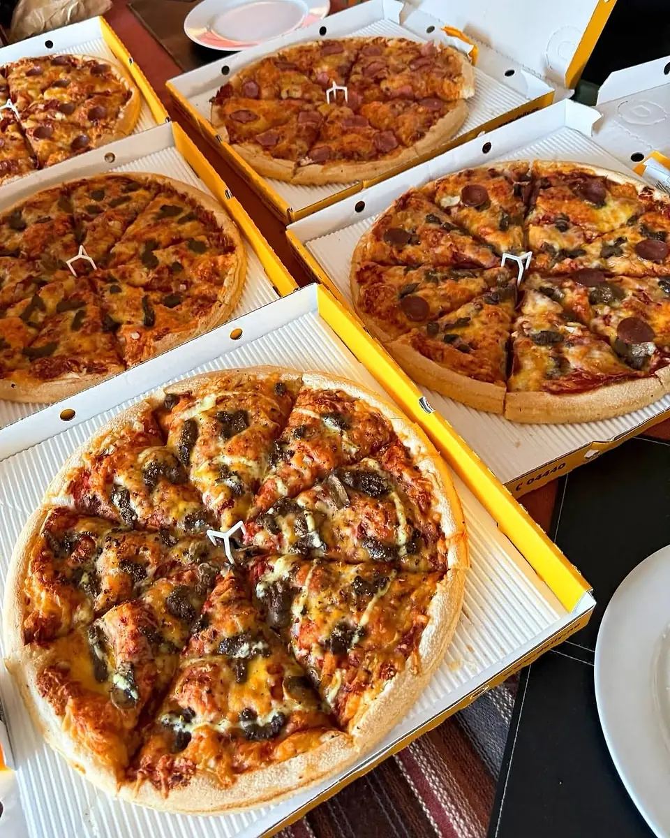 Fem Dolly-pizzaer i åpne gule Dolly-esker på et bord